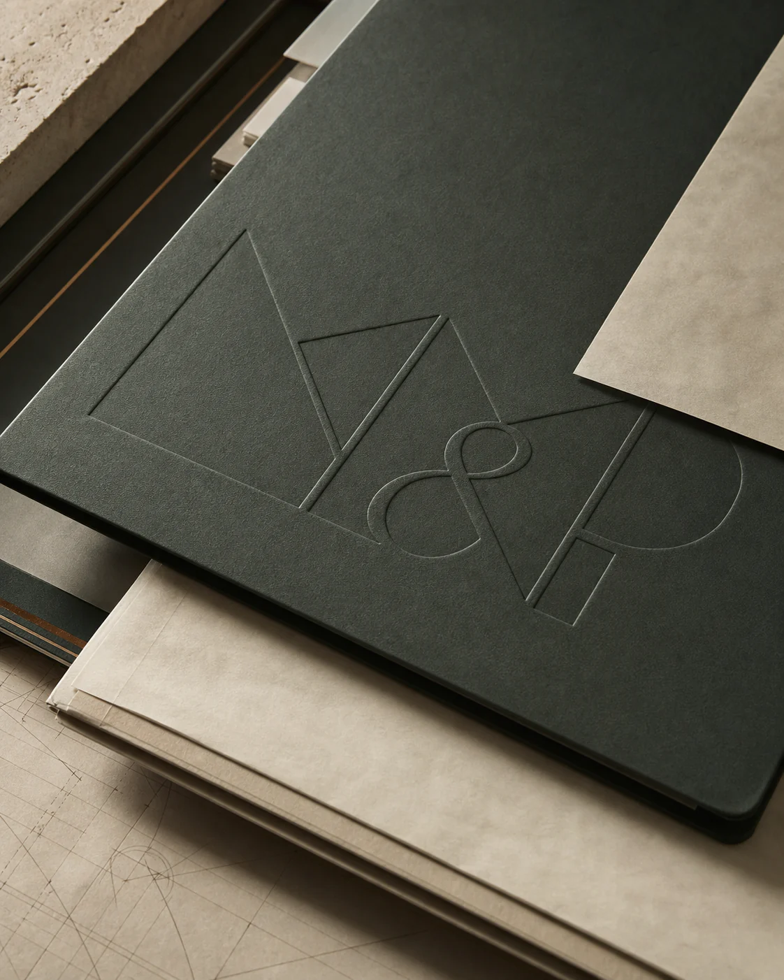 Parchment sheets and green covers follow a precise modular rhythm on a dark desk.